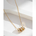 Collier pendentif triple anneaux dorés serties de zircons sur fond blanc