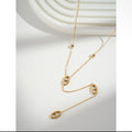 Collier lariat doré avec maillons marins ouverts et zircons sur fond blanc